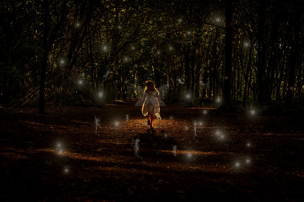 A young girl in a white dress walks through a dark forest illuminated by magical floating lights. the scene exudes an ethereal and mysterious ambiance.
