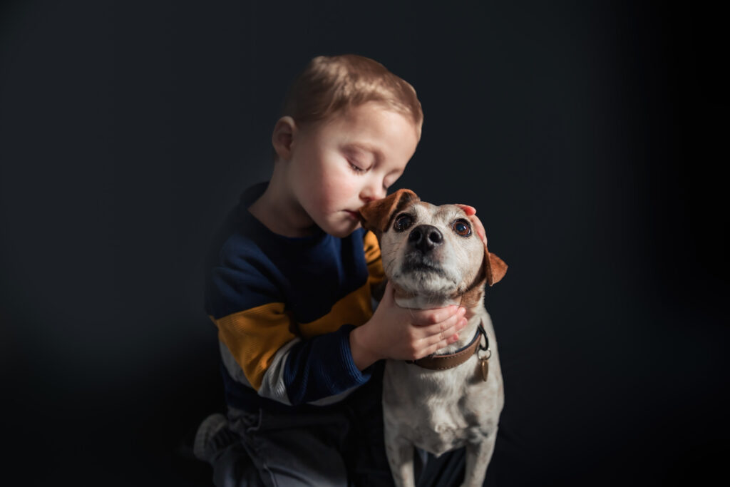 Child hugging dog, tender moment, dark background